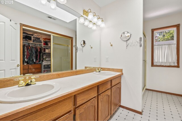 bathroom with a stall shower, tile patterned floors, baseboards, and double vanity