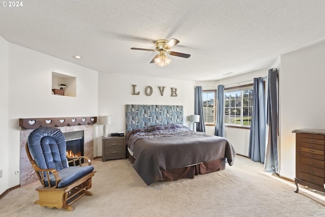 carpeted bedroom with ceiling fan, a textured ceiling, and a tile fireplace