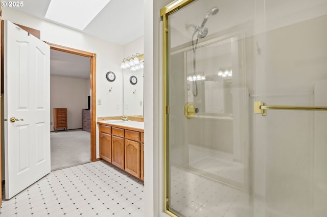 full bath featuring a shower stall, a skylight, and vanity
