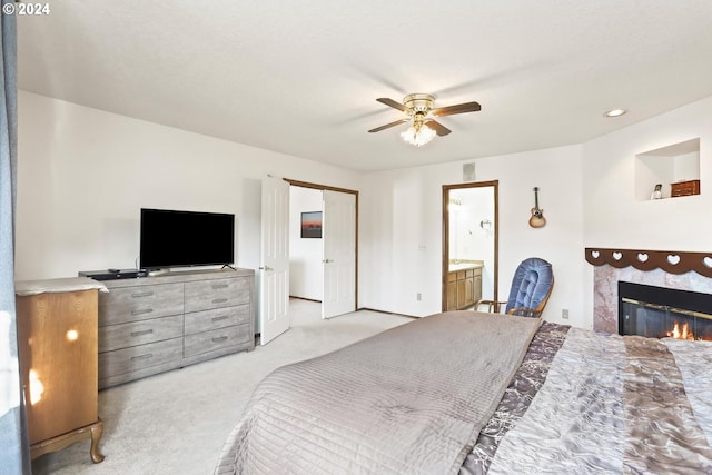 carpeted bedroom with ensuite bath and ceiling fan