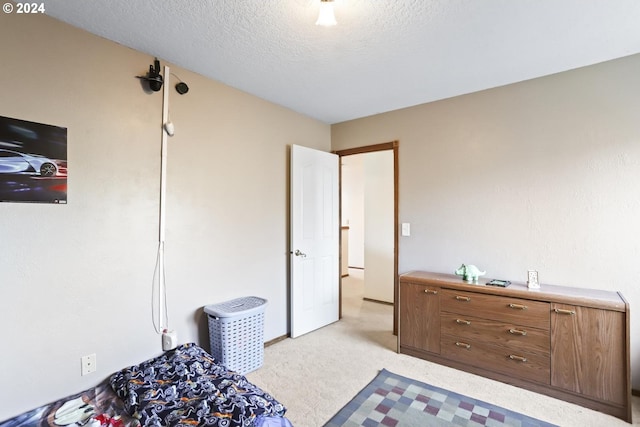 bedroom featuring light colored carpet and a textured ceiling