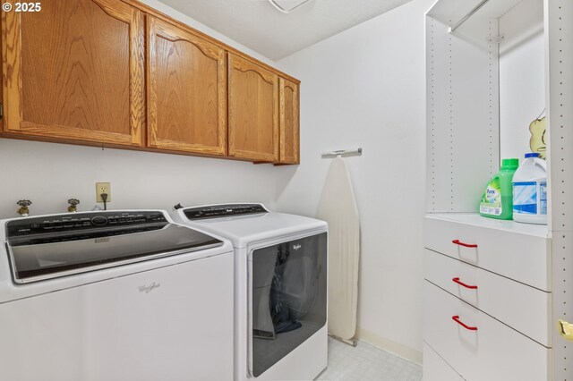 clothes washing area featuring washing machine and clothes dryer, cabinet space, and baseboards