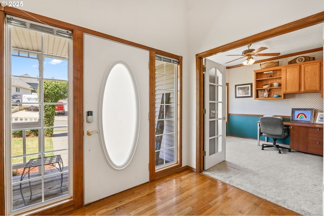 entryway with ceiling fan, light wood-style flooring, light carpet, and baseboards