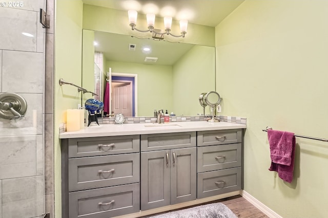 full bathroom featuring wood finished floors, visible vents, vanity, baseboards, and a tile shower