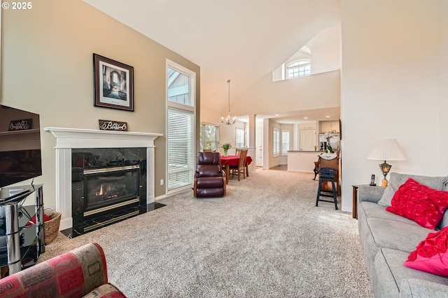 living area with a chandelier, high vaulted ceiling, a high end fireplace, baseboards, and carpet