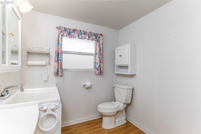 bathroom with toilet, wood-type flooring, and sink