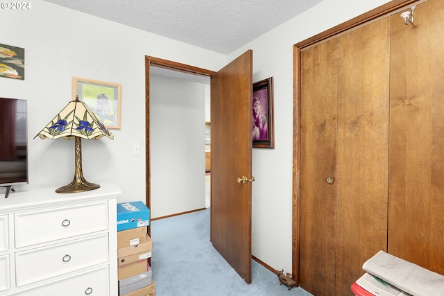 hall featuring a textured ceiling and light colored carpet