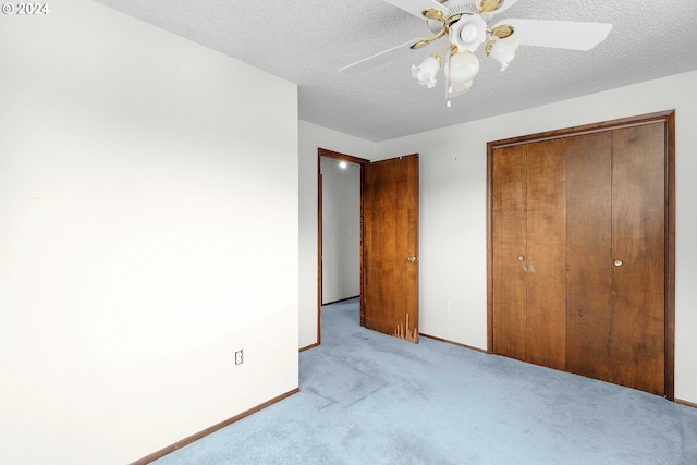 unfurnished bedroom featuring ceiling fan, light colored carpet, a textured ceiling, and a closet