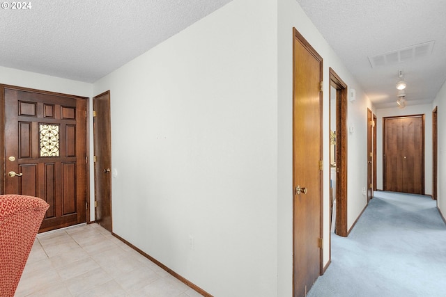 entryway with light carpet and a textured ceiling