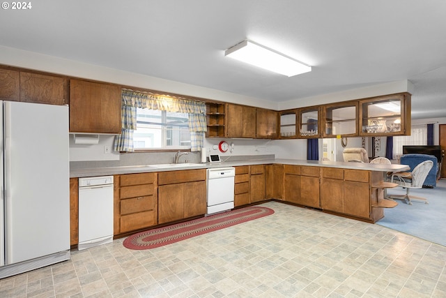 kitchen featuring kitchen peninsula, white appliances, and sink