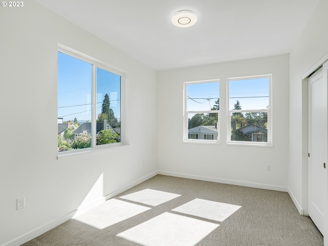 empty room with light carpet, plenty of natural light, and baseboards