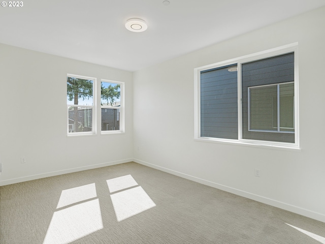 empty room featuring light carpet and baseboards