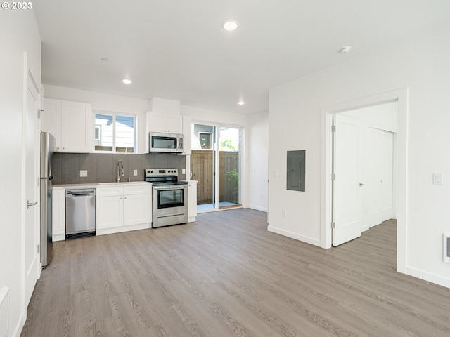 kitchen with stainless steel appliances, tasteful backsplash, white cabinetry, and light hardwood / wood-style floors