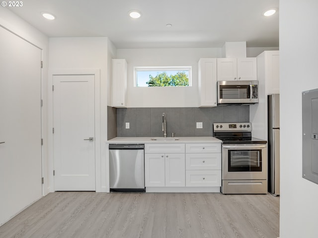 kitchen with light hardwood / wood-style flooring, stainless steel appliances, sink, decorative backsplash, and white cabinetry