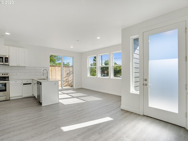 kitchen with appliances with stainless steel finishes, white cabinetry, open floor plan, and a sink