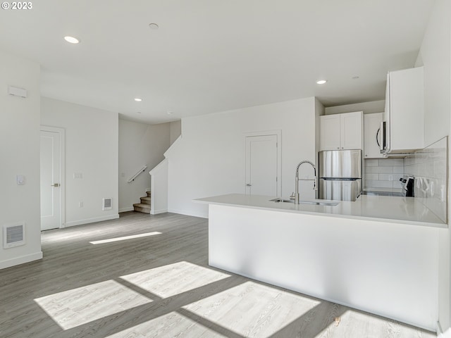 kitchen with a peninsula, a sink, visible vents, light countertops, and appliances with stainless steel finishes