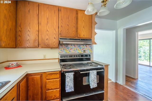 kitchen with light hardwood / wood-style flooring, black / electric stove, an inviting chandelier, and sink