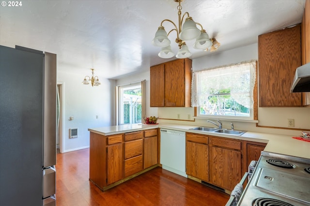 kitchen featuring white appliances, kitchen peninsula, decorative light fixtures, sink, and a chandelier