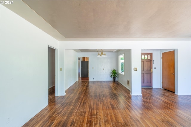 spare room with an inviting chandelier and dark hardwood / wood-style flooring