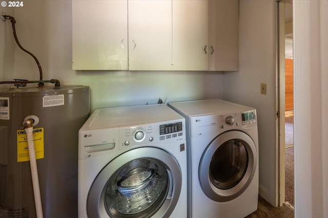 clothes washing area with water heater, washer and clothes dryer, and cabinets