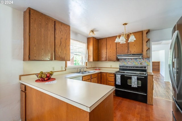 kitchen with hanging light fixtures, kitchen peninsula, black / electric stove, dark hardwood / wood-style floors, and an inviting chandelier