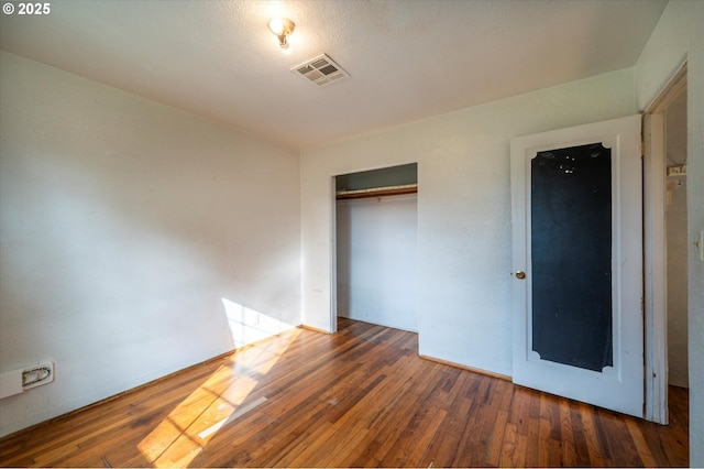 unfurnished bedroom with dark wood-type flooring and a closet