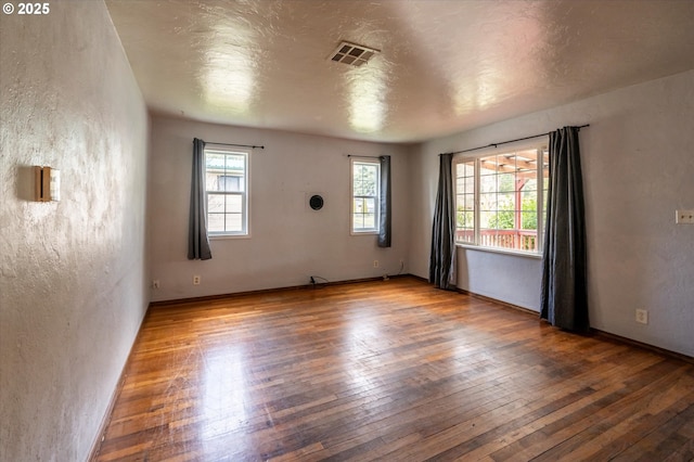 empty room with a textured ceiling and dark hardwood / wood-style flooring