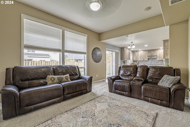 living room with an inviting chandelier, light carpet, and a textured ceiling