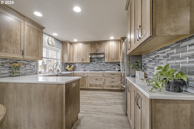 kitchen featuring sink, a textured ceiling, stainless steel gas stovetop, light hardwood / wood-style flooring, and decorative backsplash