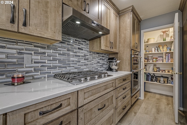 kitchen featuring stainless steel appliances, light hardwood / wood-style floors, extractor fan, light stone countertops, and decorative backsplash