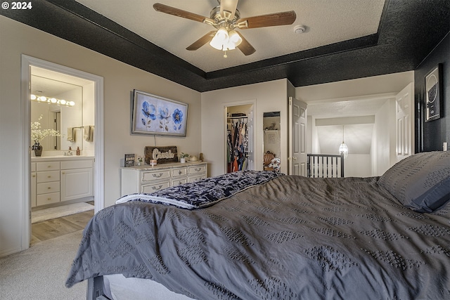 bedroom with a closet, a spacious closet, ensuite bath, a textured ceiling, and ceiling fan