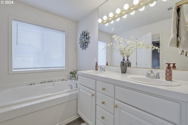 bathroom featuring vanity, a textured ceiling, and a tub