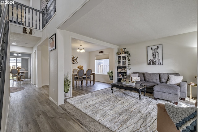 living room with a textured ceiling, a notable chandelier, a healthy amount of sunlight, and dark hardwood / wood-style floors