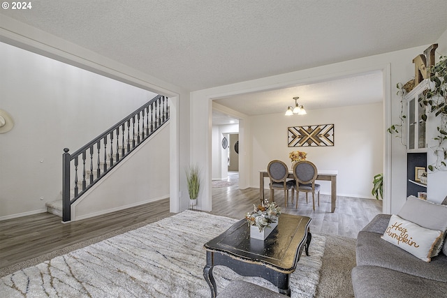 41637 NW Buckshire St, Banks, OR 97106 - living room with wood finished floors, stairway, a chandelier, a textured ceiling, and baseboards