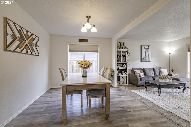 dining area featuring hardwood / wood-style floors, a textured ceiling, and an inviting chandelier