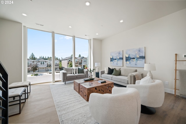 living room with recessed lighting, visible vents, a wall of windows, light wood-type flooring, and baseboards