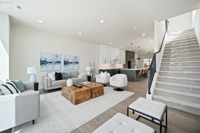 living area with recessed lighting, visible vents, stairway, and wood finished floors