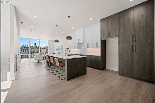 kitchen featuring a breakfast bar area, light countertops, light wood-style floors, modern cabinets, and a wall of windows