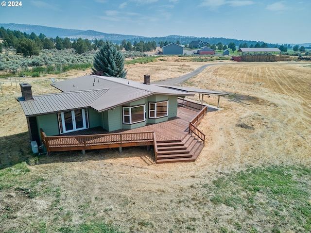 back of house with metal roof, a rural view, a mountain view, and a chimney