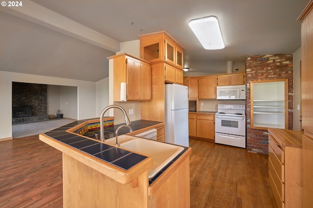 kitchen with white appliances, tile counters, dark wood-style flooring, vaulted ceiling with beams, and a peninsula