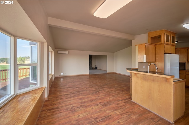 kitchen featuring dark wood-style flooring, lofted ceiling with beams, a wall mounted AC, freestanding refrigerator, and a peninsula