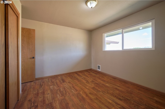 spare room featuring dark wood-type flooring, visible vents, and baseboards