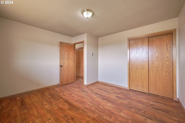 unfurnished bedroom with a closet, baseboards, and wood finished floors