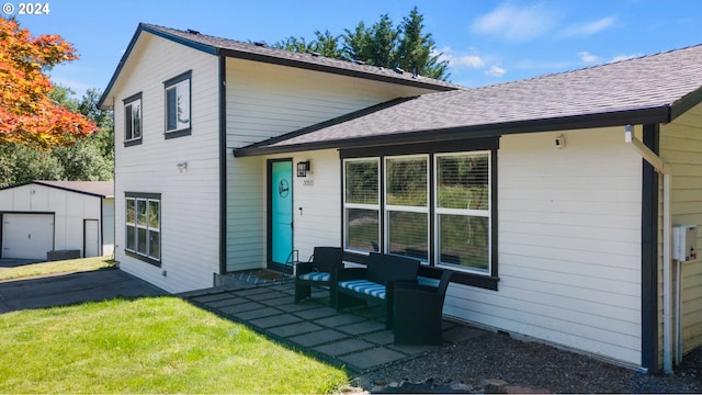 back of house with a garage, a patio, a lawn, and an outdoor structure