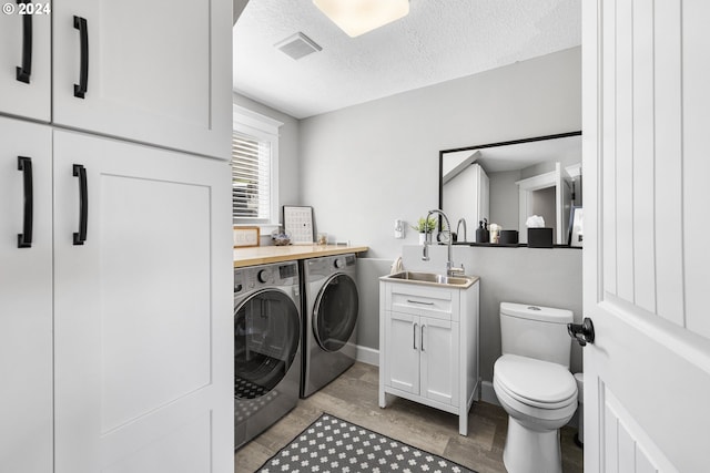 laundry room with separate washer and dryer, a textured ceiling, light hardwood / wood-style floors, and sink