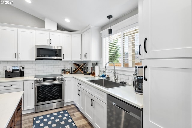 kitchen featuring lofted ceiling, white cabinets, appliances with stainless steel finishes, and sink