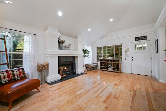 interior space featuring high vaulted ceiling, light wood-type flooring, and a tile fireplace