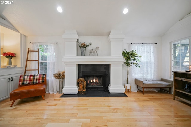 sitting room featuring light hardwood / wood-style floors, lofted ceiling, and a fireplace