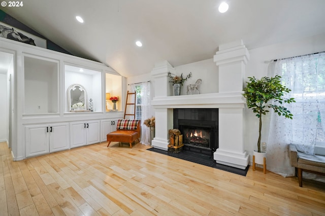 sitting room featuring a fireplace, light hardwood / wood-style floors, and lofted ceiling