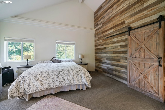 carpeted bedroom with a barn door, wood walls, and high vaulted ceiling